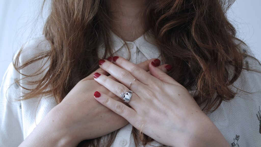 A woman with hands over her heart, symbolizing self-care and emotional healing.