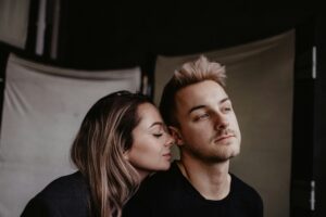 Two people looking at each other from a distance on a couch, expressing the quiet tension of navigating vulnerability.