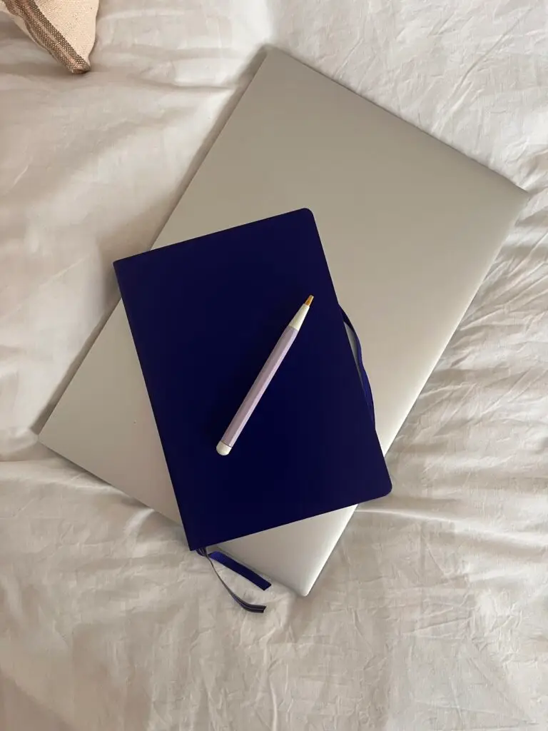 Notebook and computer on a bed.