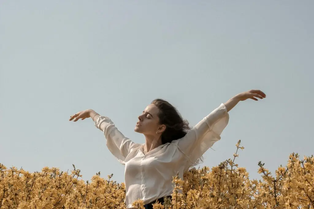 Woman with her hands in the air in a field.