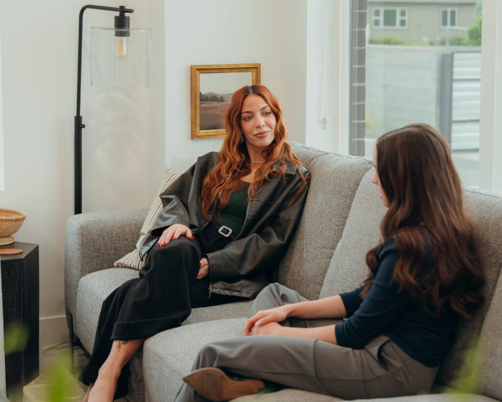 Clarissa Mace, MFT therapist, and Grace Samuels, UMFTI, sitting on a couch.