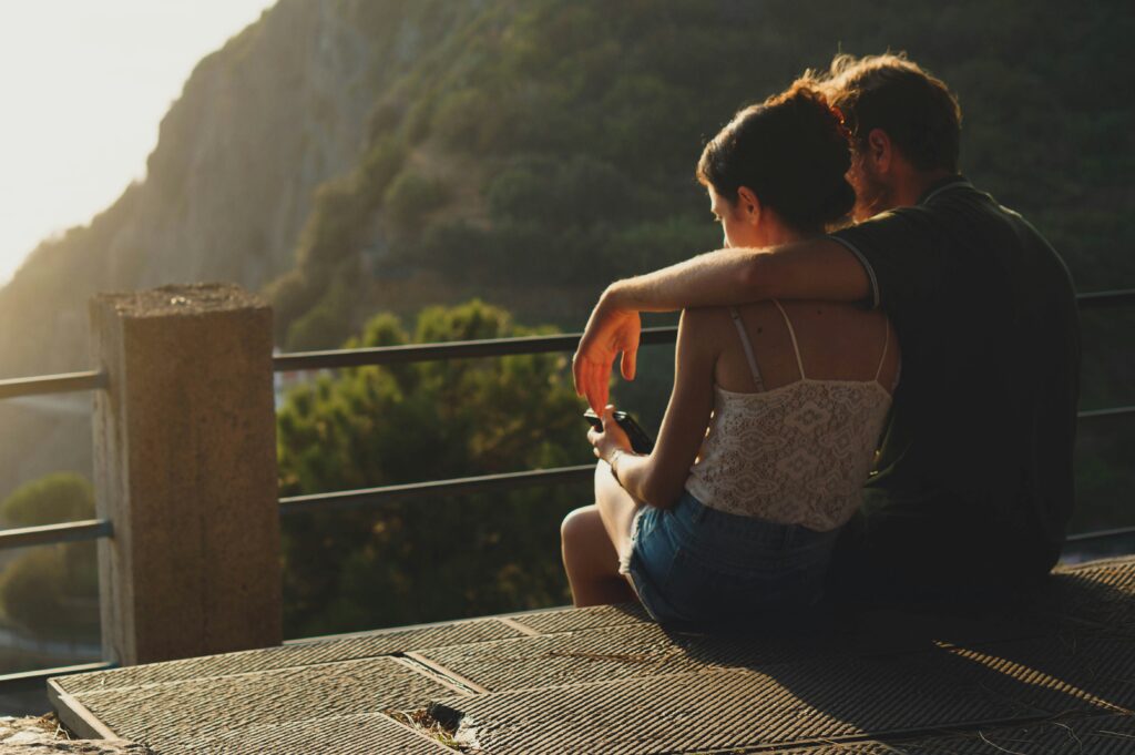 A couple sitting together overlooking a mountain view, suggesting peace and reflection after counseling.