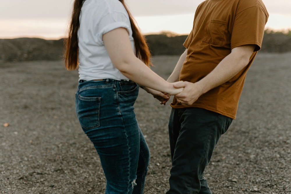 A married couple holding hands in an open field.