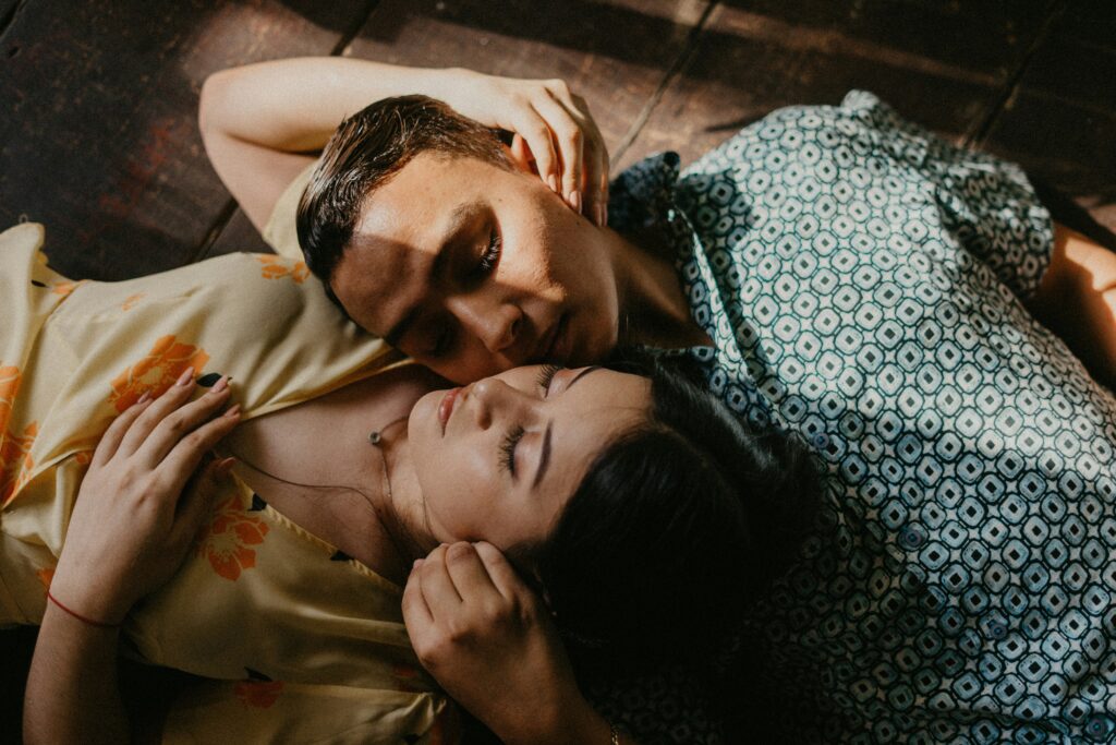 A couple lying together with closed eyes, expressing calm and emotional connection.