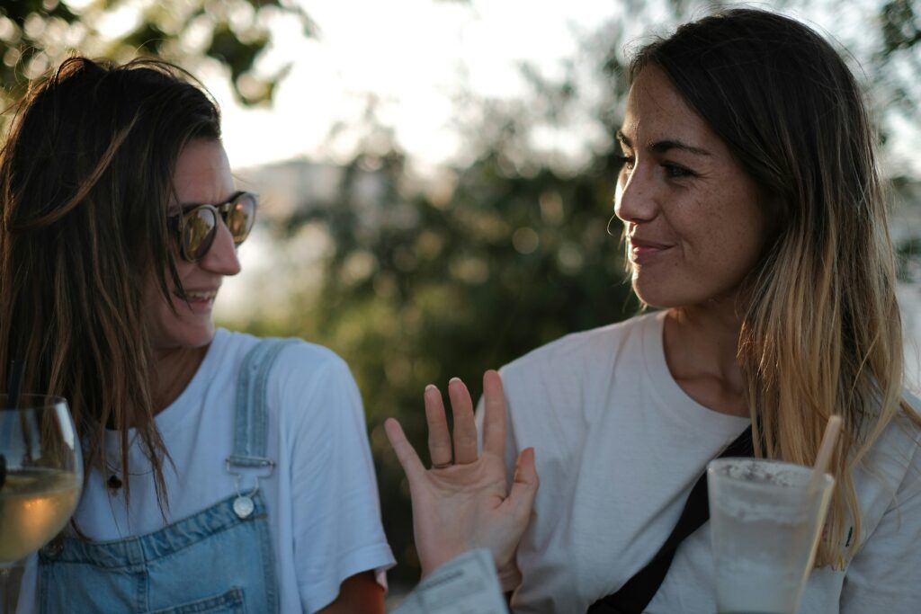 Two women smiling and talking across the table, enjoying a lighthearted connection.