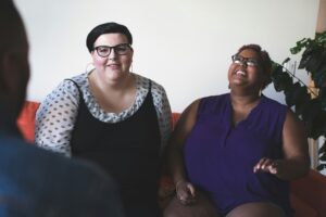 Two women in a counseling session, seated and engaged in a supportive conversation with their therapist.