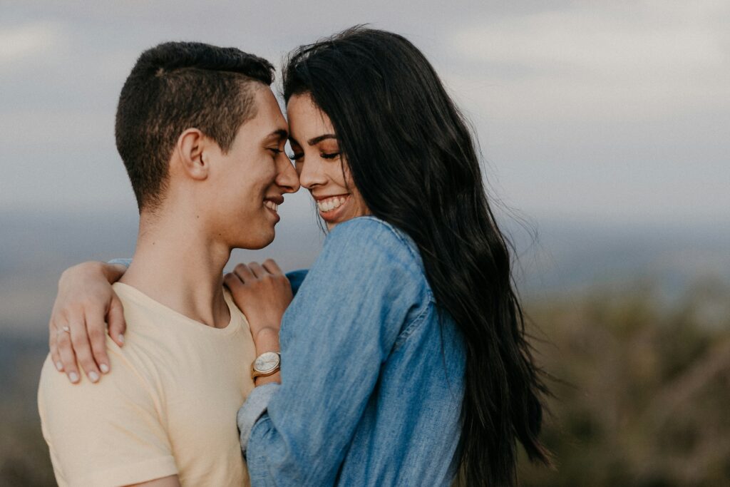 A couple smiling and embracing forehead-to-forehead, showing emotional closeness.