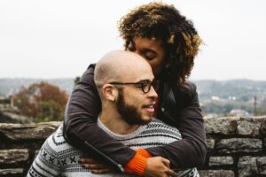 A woman embracing a man from behind, resting her head gently against him, symbolizing support during emotional times.