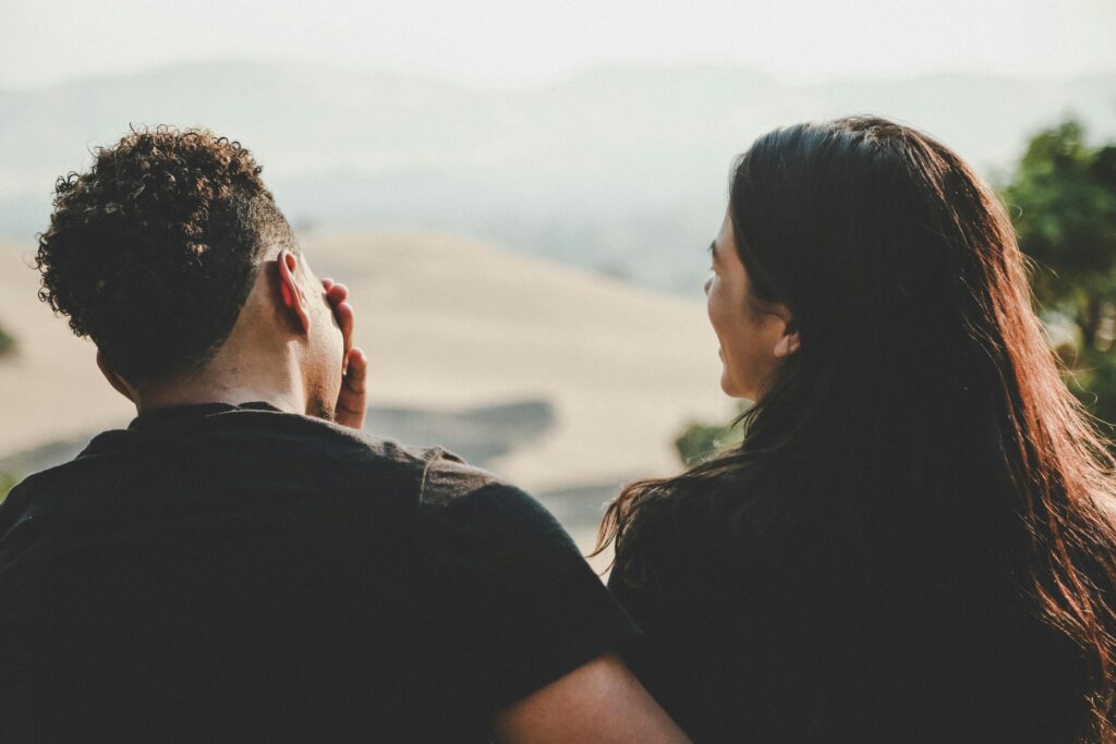 A couple sitting outdoors, one person listening attentively while the other shares emotionally.
